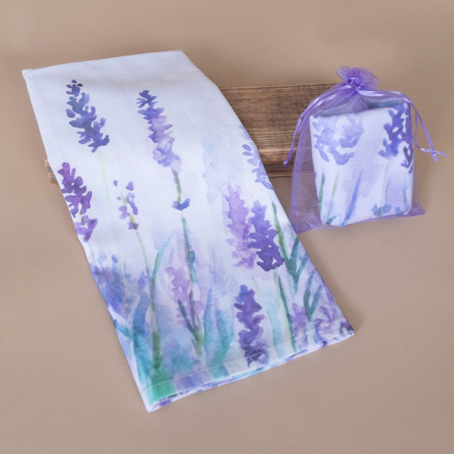 Lavender-themed kitchen towel displayed flat and packaged in an small purple bag on a beige background