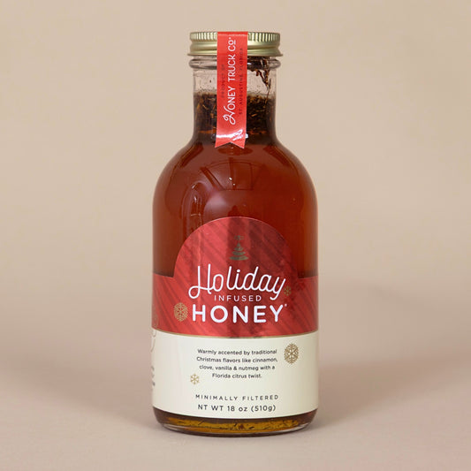 Holiday Honey bottle with a festive red label displayed on a beige background for a seasonal treat