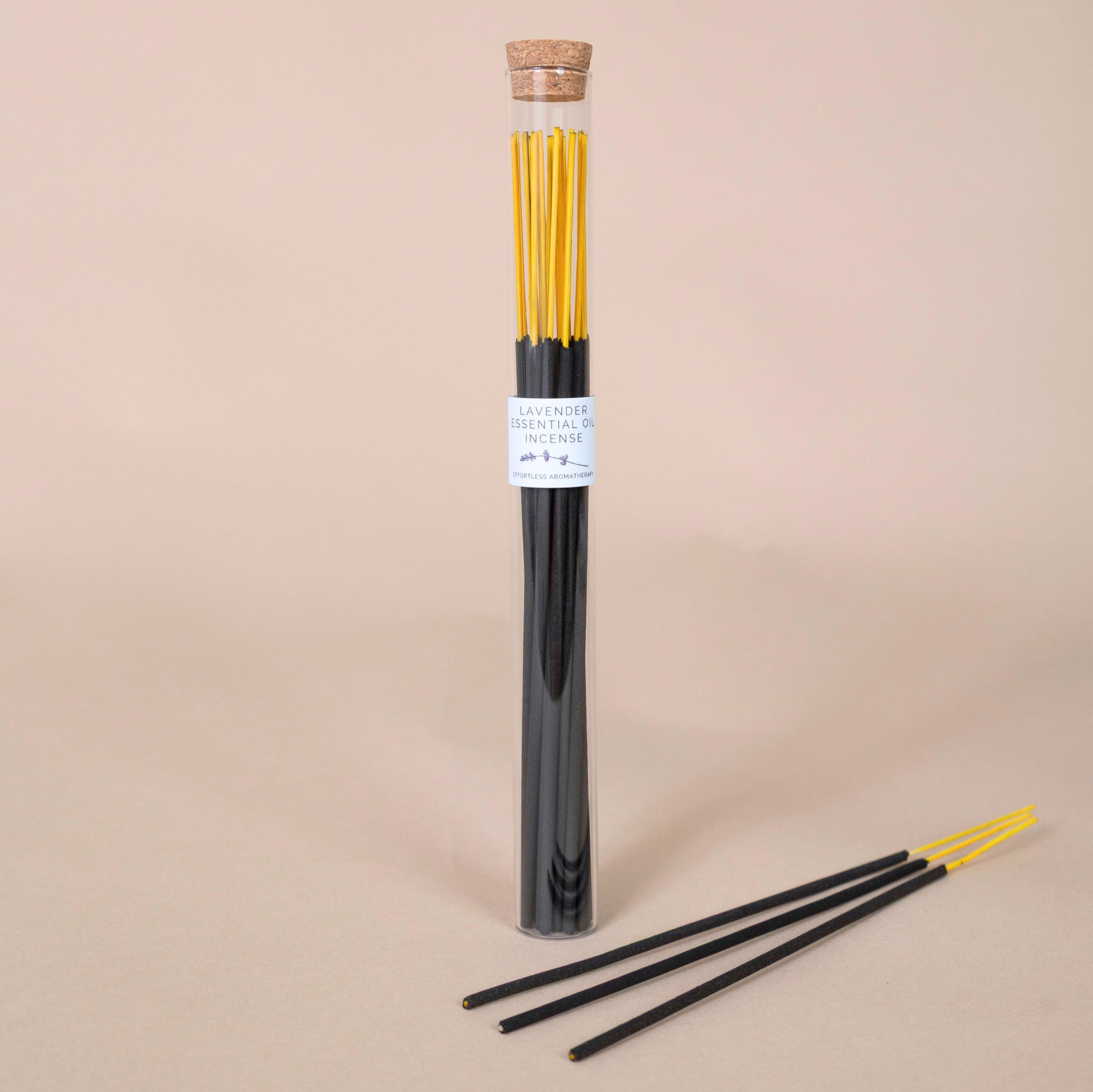 Tube of lavender incense sticks with three sticks displayed in front on a beige background