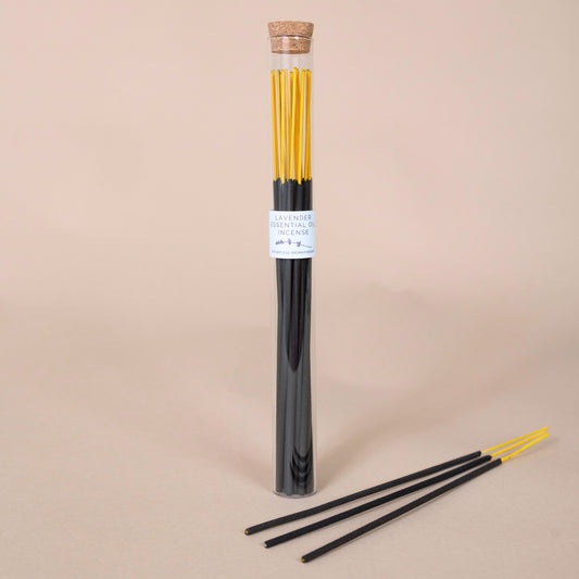 Tube of lavender incense sticks with three sticks displayed in front on a beige background