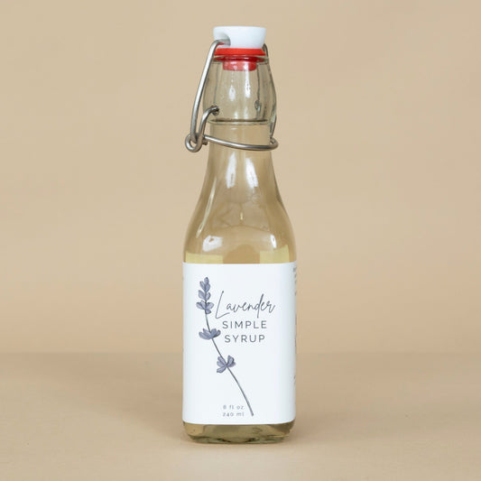 Lavender Simple Syrup displayed in a clear bottle with fresh lavender sprigs highlighting its natural purple hue