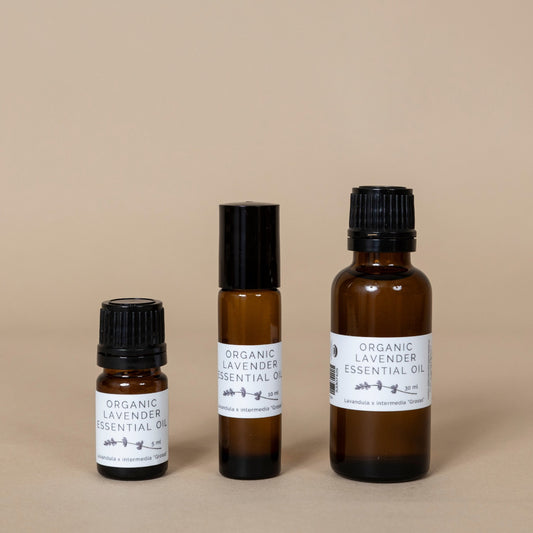 Organic Lavender Essential Oil in an amber glass bottle with a dropper, shown on a wooden surface with fresh lavender flowers