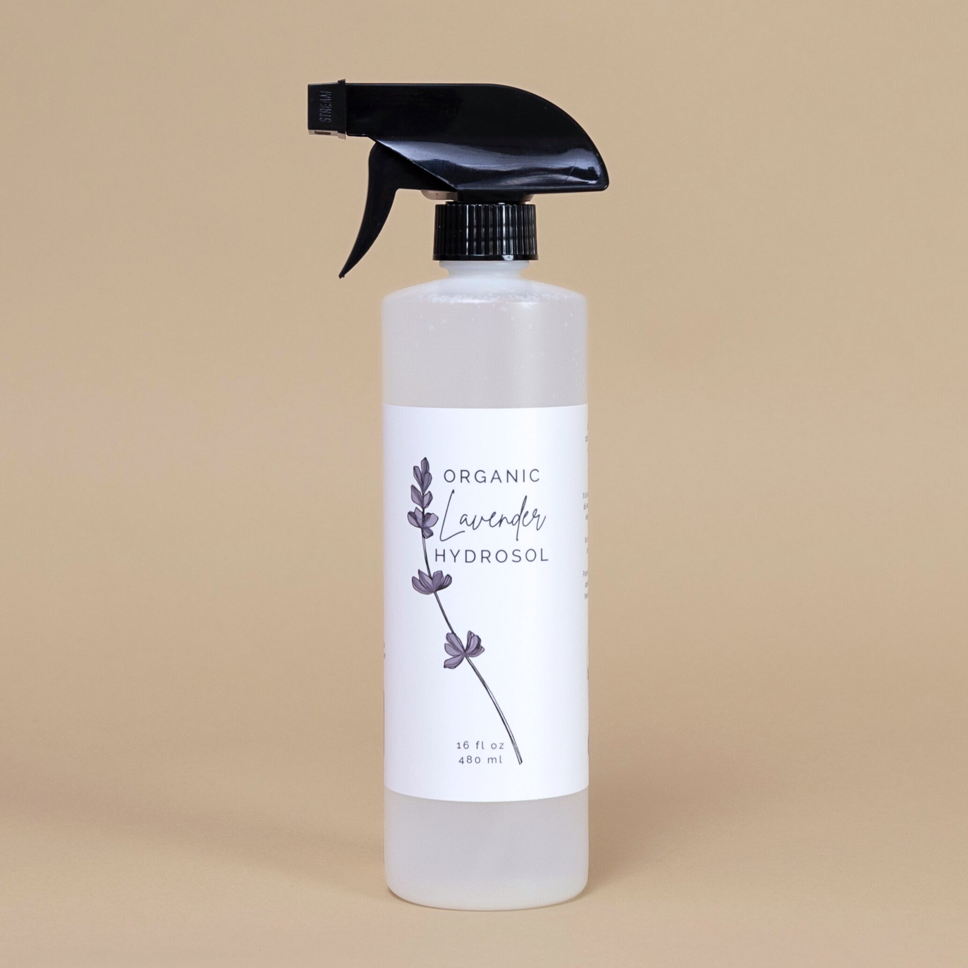 Frosted white bottle of organic lavender hydrosol on a beige backgrouud