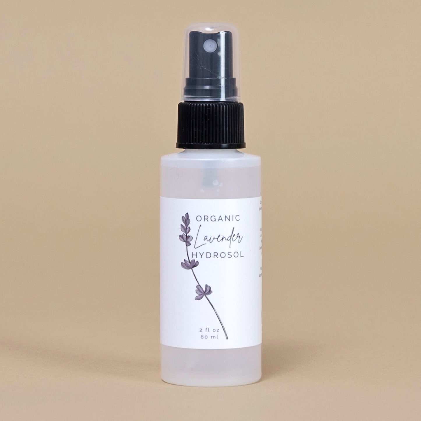 Frosted white bottle of organic lavender hydrosol on a beige backgrouud